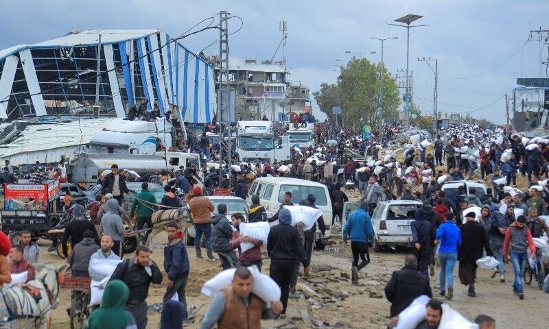 Palestinians carry bags of flour they grabbed from an aid truck near an Israeli checkpoint. &mdash; Reuters
