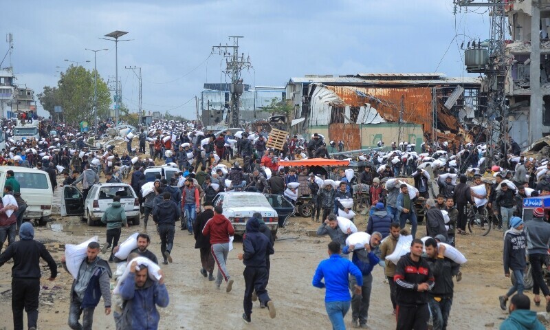 Palestinians carry bags of flour they grabbed from an aid truck near an Israeli checkpoint. &mdash; Reuters