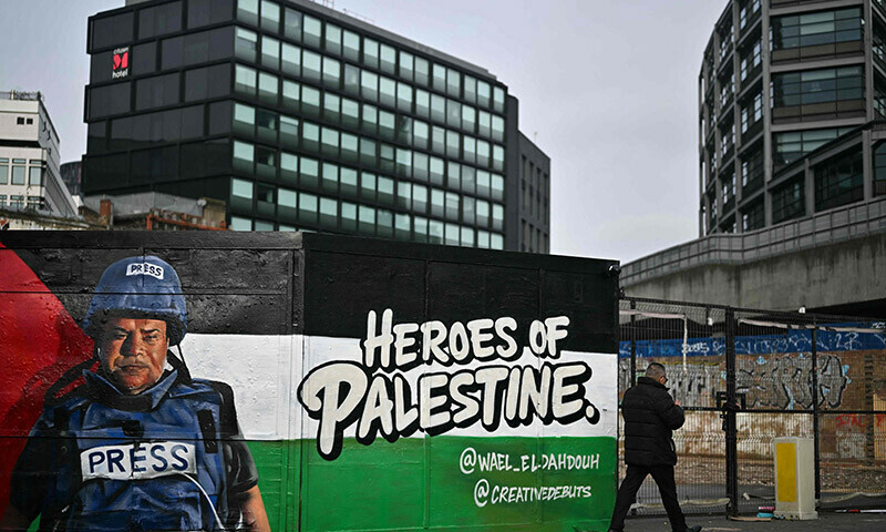 A pedestrian walks past a graffiti made by Spanish street artist Nacho Welles, also known as Core246, depicting Palestinian journalist and bureau chief of Al Jazeera in Gaza City Wael al-Dahdouh, as part of a project launched by the art platform Creative Debuts called &ldquo;Heroes of Palestine&rdquo;, in east London, on January 29. &mdash; AFP