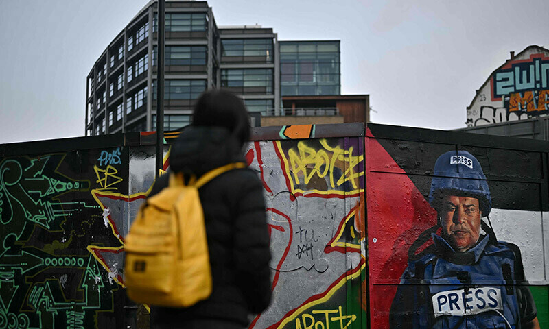 A pedestrian walks past a graffiti made by Spanish street artist Nacho Welles, also known as Core246, depicting Palestinian journalist and bureau chief of Al Jazeera in Gaza City Wael al-Dahdouh, as part of a project launched by the art platform Creative Debuts called &ldquo;Heroes of Palestine&rdquo;, in east London, on January 29. &mdash; AFP
