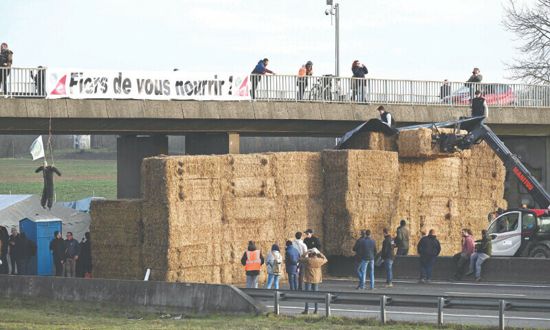  Paris: A banner reading &lsquo;Proud to feed you!&rsquo; is seen at a road blockage held by farmers on the A4 highway near Jossigny, on Monday.&mdash;AFP 