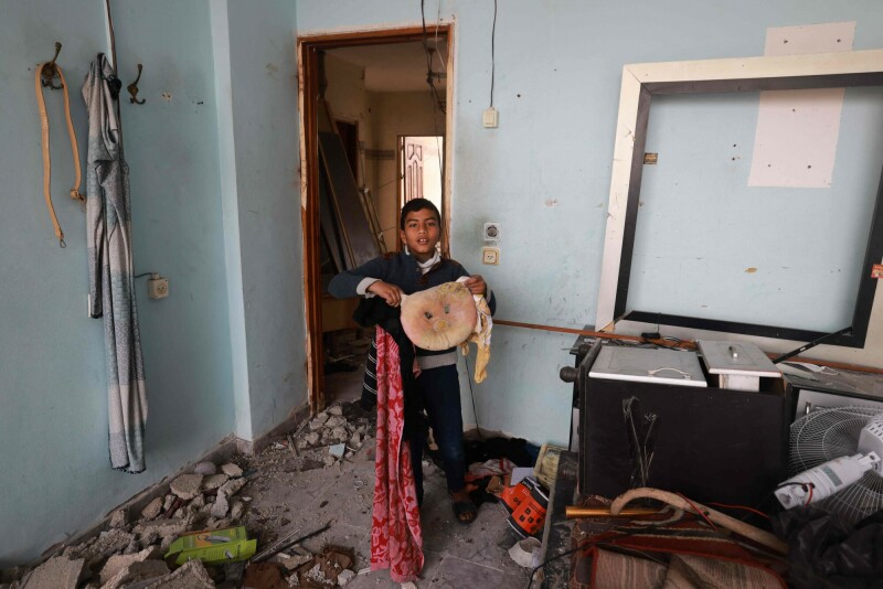 A boy salvages a pillow, inside a house damaged by Israeli overnight bombardment in Rafah in the southern Gaza Strip on February 25. &mdash; AFP