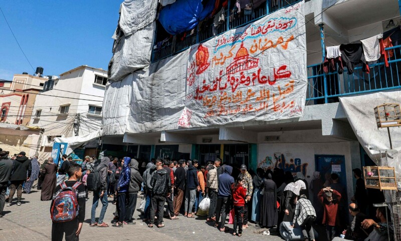  Palestinians gather to receive humanitarian aid at a camp in a school run by UNRWA in Rafah in the southern Gaza Strip on March 13, 2024. &mdash; AFP 