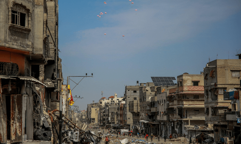 Humanitarian aid parcels attached to parachutes are airdropped from a military aircraft over the Gaza Strip on March 21, 2024. — AFP