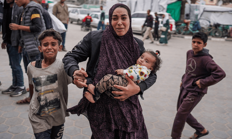  A Palestinian woman holding her children reacts outside a hospital where casualties are brought following Israeli bombardment in Bureij, central Gaza Strip, on April 8. &mdash; AFP 
