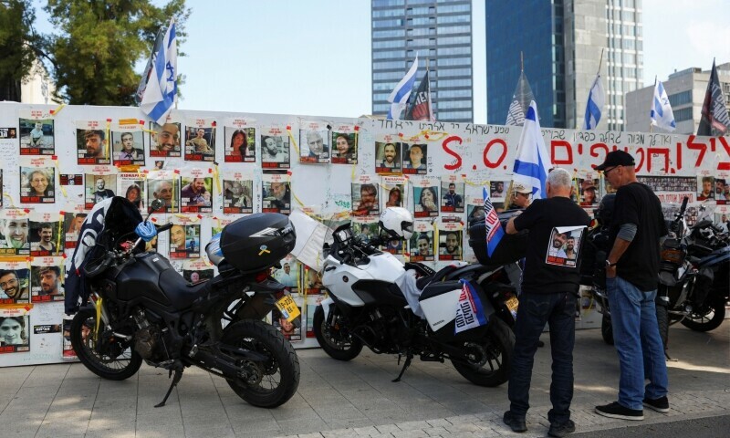 People stand next to a wall with posters of hostages and Israeli flags as they participate in &lsquo;Ride for Hope&rsquo;, an event where people ride motorcycles across the country in support of hostages kidnapped in the October 7 attack on Israel by Hamas, in Tel Aviv, Israel on April 12. &mdash; Reuters