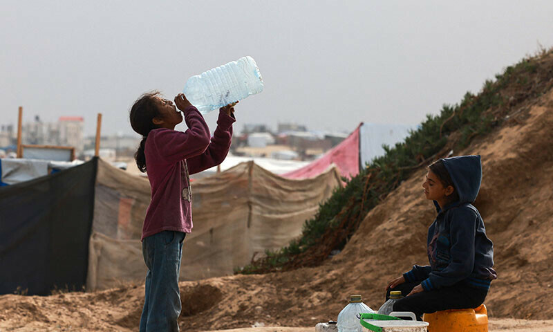 Displaced Palestinian children wait for a water supply tank amid soaring temperatures at a tent camp in Rafah on April 26. &mdash; AFP