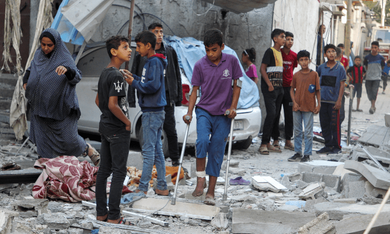  A wounded Palestinian walks with crutches as others gather at the site of an Israeli strike on a house in Rafah, in the southern Gaza Strip on May 9. &mdash; Reuters 