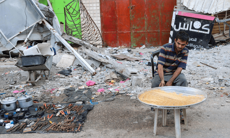 A Palestinian man sells sweets near tools and pots taken from the rubble of buildings for sale, in Gaza City on June 10, 2024. &mdash; AFP