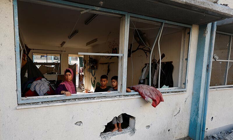 Palestinians look through the damaged windows of a classroom in a UNRWA school, after an air strike on a neighbouring house in Khan Younis on June 21. &mdash; Reuters