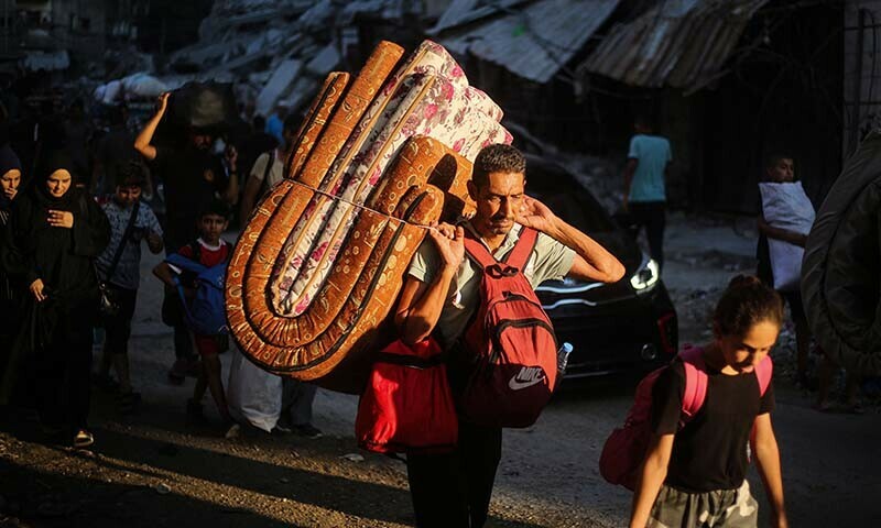 Palestinians carrying their personal belongings flee the al-Bureij refugee camp in the central Gaza Strip on July 28. &mdash; AFP