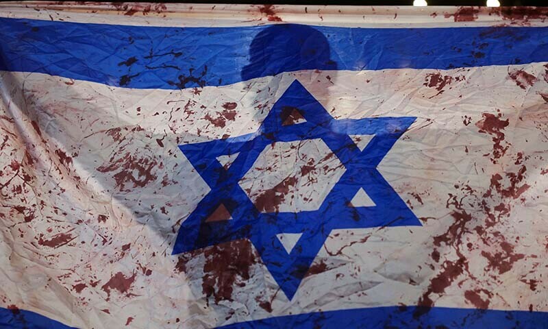  A person holds an Israeli flag stained with red paint to mimic blood during a protest against Israeli Prime Minister Benjamin Netanyahu&rsquo;s government in Tel Aviv on August 10. &mdash; Reuters 