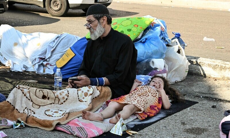 A man and a child who fled Israeli bombardment on Beirut&rsquo;s southern suburbs, sit with some of their belongings in the Lebanese capital&rsquo;s downtown district where they spent the night. &mdash; AFP