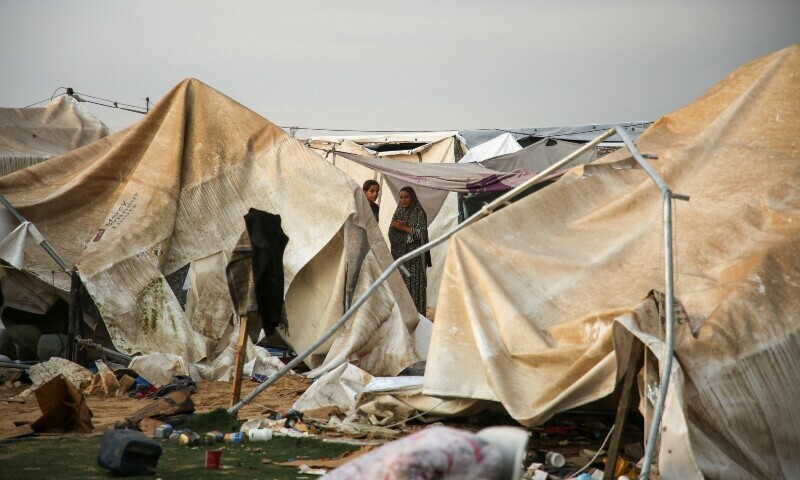 Women look on, as Palestinians inspect the damage at the site of an Israeli strike on a tent camp sheltering displaced people, amid the ongoing Gaza conflict, in Al-Mawasi area in Khan Younis, in the southern Gaza Strip on October 15. &mdash; Reuters