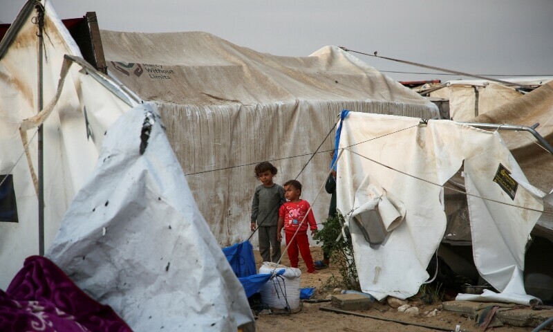Children look on, as Palestinians inspect the damage at the site of an Israeli strike on a tent camp sheltering displaced people, amid the ongoing Gaza conflict, in Al-Mawasi area in Khan Younis, in the southern Gaza Strip on October 15. &mdash; Reuters