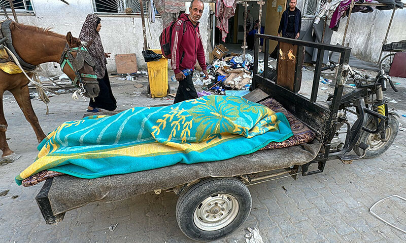 A body lies covered by a blanket on a cart outside the Kamal Adwan Hospital in Beit Lahia in the northern Gaza Strip on October 28. — AFP