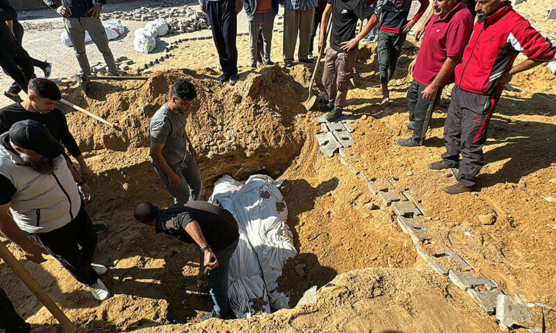 Palestinians bury bodies during a funeral in Beit Lahia, in the northern Gaza Strip, on October 29. — AFP