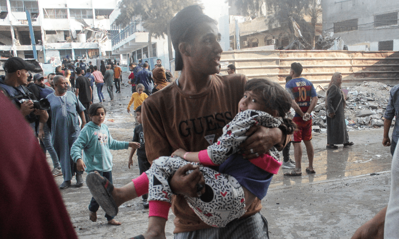  A Palestinian carries a child after a school sheltering displaced people was hit by an Israeli strike, at Beach camp in Gaza City on November 7. &mdash; Reuters 