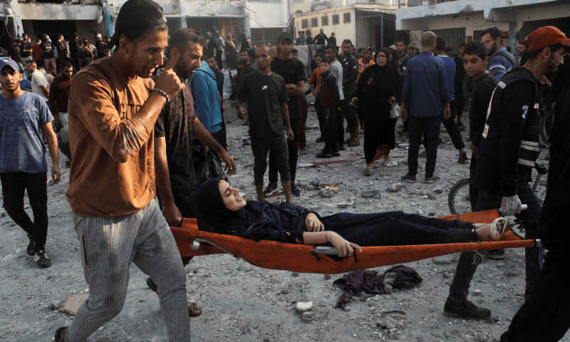  Palestinians carry an injured woman on a stretcher after a school sheltering displaced people was hit by an Israeli strike, at Beach camp in Gaza City on November 7. &mdash; Reuters 
