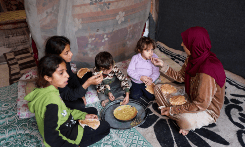 Itimad Al-Qanou, a displaced Palestinian mother from Jabalia, eats with her children inside a tent in Deir Al-Balah, central Gaza Strip on November 9. — Reuters