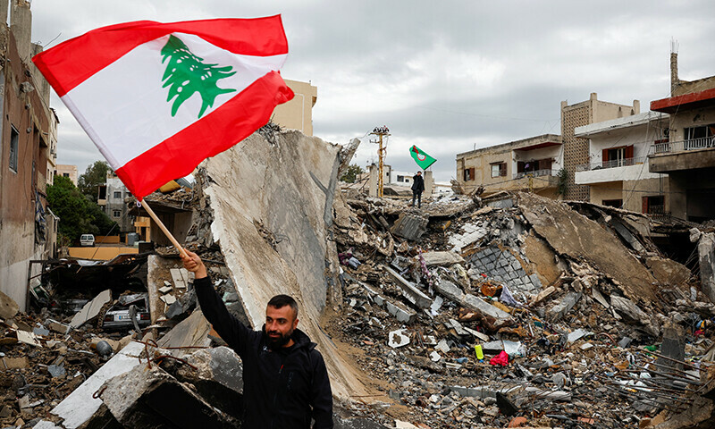 A man waves a Lebanese flag as he stands amidst the rubble of a building destroyed in Israeli strikes, after a ceasefire between Israel and Hezbollah took effect at 0200 GMT on Wednesday after US President Joe Biden said both sides accepted an agreement brokered by the United States and France, in Tyre, Lebanon on November 27. &mdash; Reuters