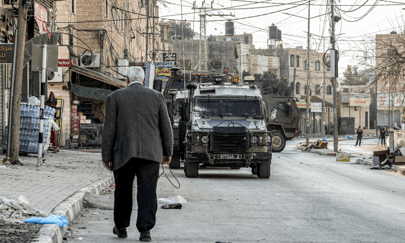  An elderly Palestinian man walks by as Israeli army armoured vehicles move along a road in the Palestinian village of Qabatiyah, in the north of the occupied West Bank, on January 10, 2025. &mdash; AFP 
