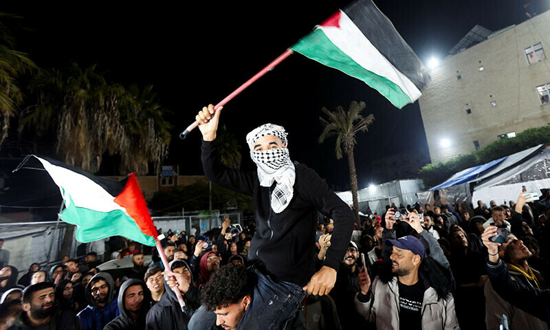 A man waves Palestinian flags as Palestinians react to news of a ceasefire deal with Israel, in Deir Al-Balah in the central Gaza Strip on January 15. — Reuters