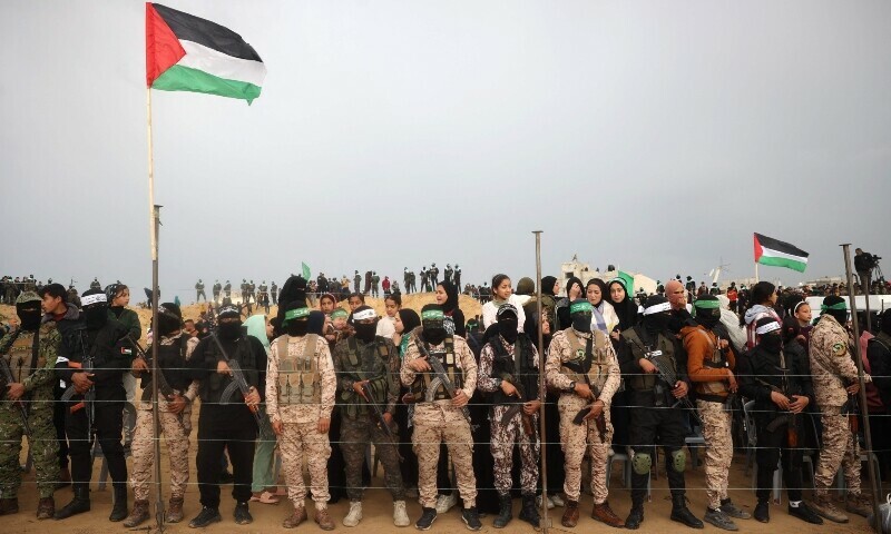 Hamas fighters stand at attention ahead of the handing over the bodies of four Israeli hostages in Khan Younis in southern Gaza. — AFP