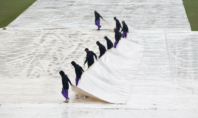 Staff cover the pitch as rain delays the start of play. — Reuters