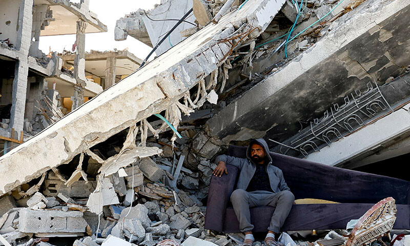 A Palestinian man sits amidst the rubble of buildings destroyed during the Israeli offensive, amid a ceasefire between Israel and Hamas, in Rafah in the southern Gaza Strip on February 16. &mdash; Reuters