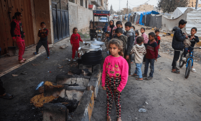 Palestinian children queue at a charity kitchen ahead of the iftar fast-breaking meal during the Muslim holy month of Ramadan, near building rubble at the Bureij refugee camp in the central Gaza Strip on March 5. — AFP