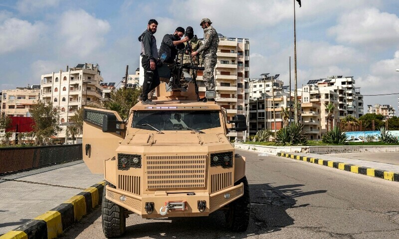 Security forces loyal to the Syrian government attach a turret to an armoured vehicle parked along a road in Syria’s western city of Latakia on March 9. — AFP