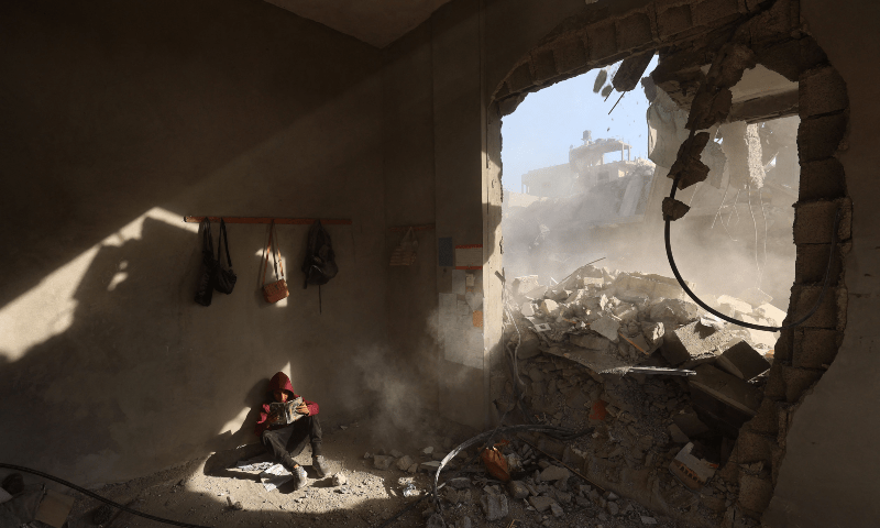  A Palestinian boy holds a book as he sits in rubble of a house, following overnight Israeli strikes, at the Nuseirat refugee camp in the central Gaza Strip on April 29, 2025. &mdash; AFP 