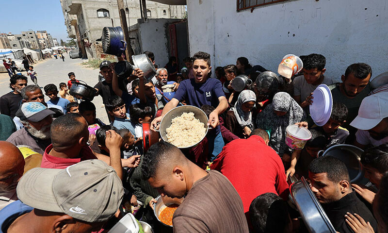 Palestinians queue to receive a food portion from a charity kitchen in the Bureij refugee camp in the central Gaza Strip on April 29. &mdash; AFP