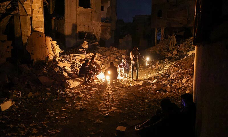 Palestinians gather in wait for the arrival of trucks carrying humanitarian aid near Jabalia, in the northern Gaza Strip late on June 15. &mdash; AFP