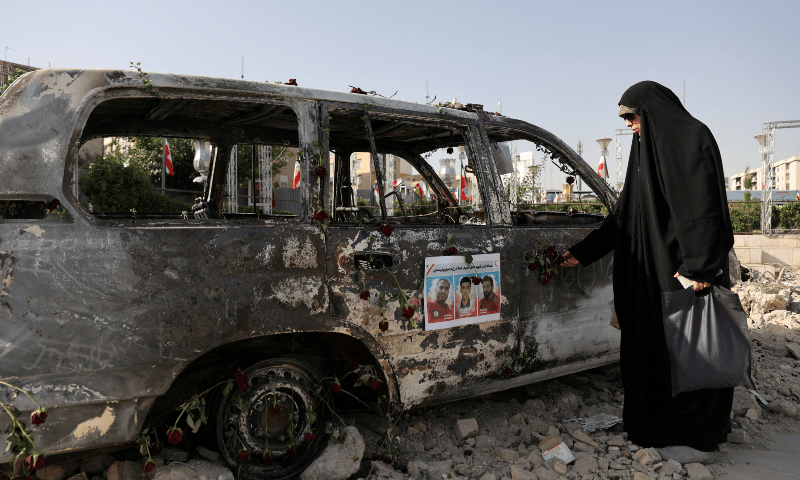 A woman looks at an ambulance burned by Israeli attacks on a street, amid the Iran-Israel conflict, in Tehran, Iran on June 23, 2025. &mdash;Majid Asgaripour/WANA (West Asia News Agency) via Reuters