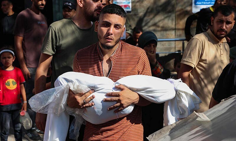 A Palestinian man carries the shrouded body of a relative killed in an Israeli strike on Al-Baqa cafeteria on Gaza City seafront, at the city’s Al-Shifa hospital on June 30. — AFP