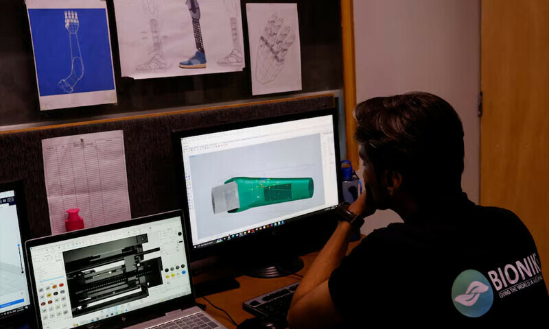 A technician works on computers with prosthetic limb diagram at Bioniks in Karachi, April 29, 2024. — Reuters