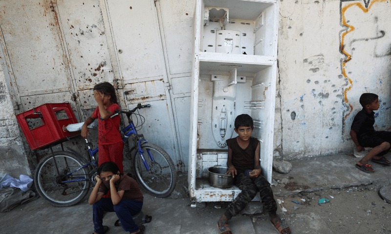  A Palestinian child sits in an empty, broken refrigerator as he waits to receive food from a charity kitchen, amid a hunger crisis, in Gaza City on July 14, 2025. &mdash; Reuters 