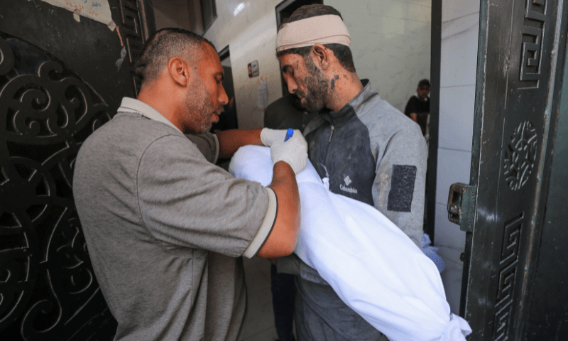  A man writes the name on the shroud covering the body of Ameer Azzam, a Palestinian child killed in an overnight Israeli strike on a house, according to medics, at Al-Shifa hospital in Gaza City on July 15, 2025. — Reuters 