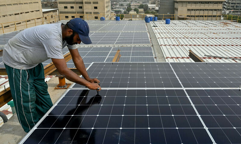Technicians install solar panels on the rooftop of a factory in Karachi, on July 2, 2025. — AFP