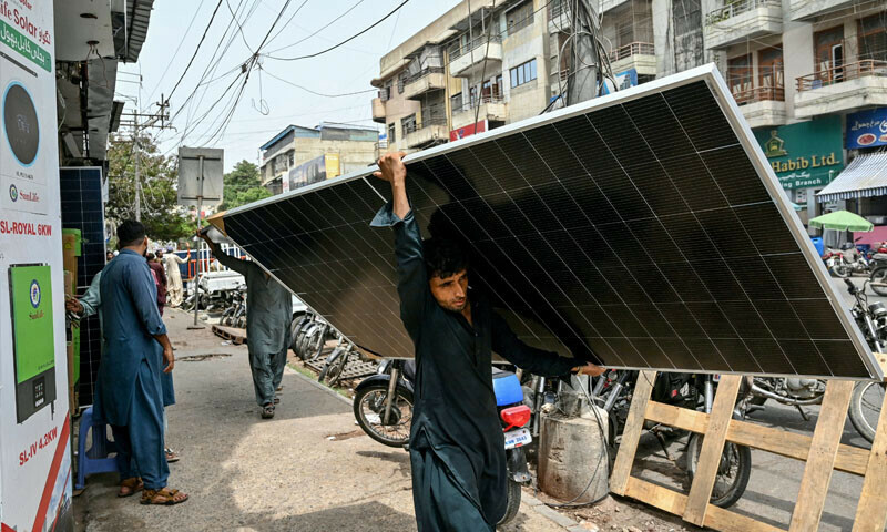 A labourer carries a solar panel along a road in Pakistan’s port city of Karachi, on June 23, 2025. — AFP