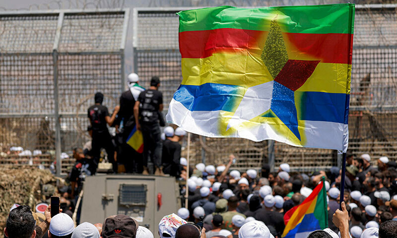 Members of the Druze community demonstrate before Israeli forces by the barbed-wire fence separating the Israeli-annexed Golan Heights and Syria near Majdal Shams on July 16. — AFP