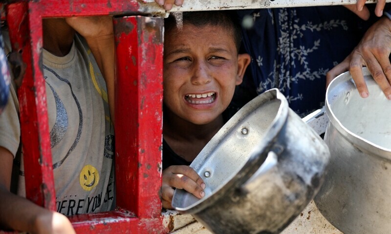 A child reacts as Palestinians gather to receive food from a charity kitchen, amid a hunger crisis, in Gaza City. — Reuters