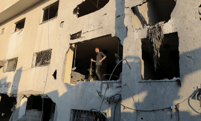  Palestinians look on while standing at the site of an overnight Israeli air strike on a house in Gaza City on July 23, 2025. &mdash; Reuters 