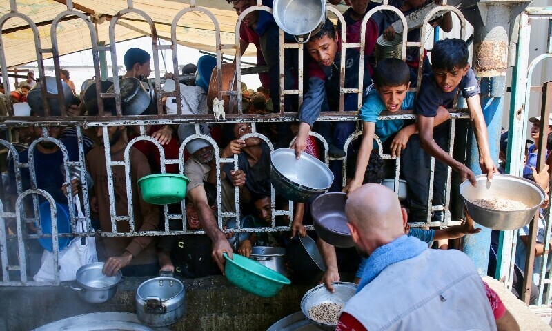 Palestinian children wait for a meal at a charity kitchen in the Mawasi area of Khan Younis in the southern Gaza Strip on July 22. &mdash; AFP