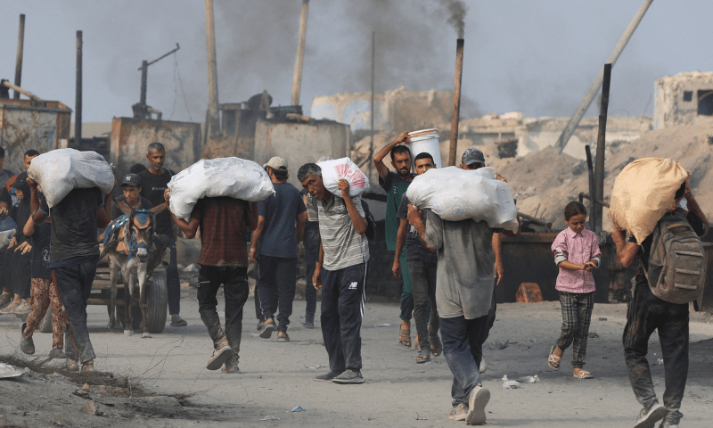  Palestinians carry aid supplies they collected from trucks that entered Gaza through Israel, in Beit Lahia, in the northern Gaza Strip on August 10, 2025. &mdash; Reuters 