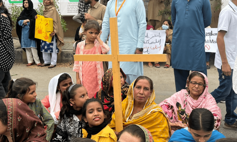 A woman holds up a wooden cross as she sits outside the YMCA at the Minority Rights March in Karachi on August 10, 2025. — Photo by Anushe Engineer