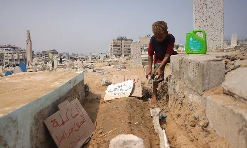 A Palestinian boy adjusts stones around the grave of Al Jazeera correspondent Anas al-Sharif, who was killed alongside other journalists in an Israeli strike, at a cemetary in Gaza City on August 12, 2025. &mdash; AFP