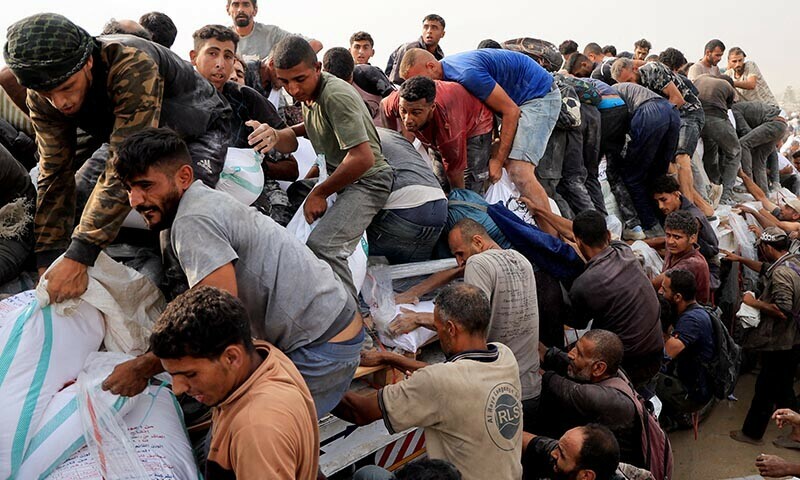 Palestinians scramble to collect aid supplies from trucks that entered through Israel, in Khan Younis, southern Gaza Strip, August 12, 2025. &mdash; Reuters